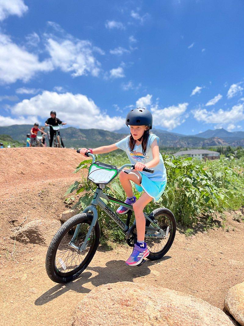 A young girl riding a bike on a dirt track