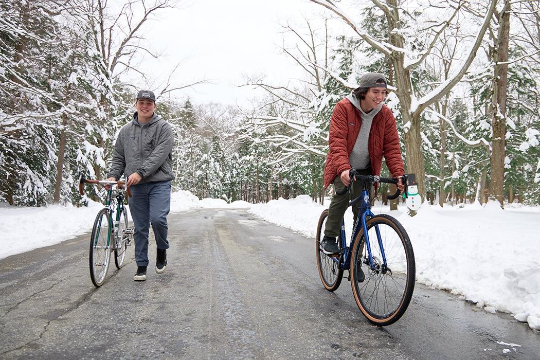 Two young people riding bikes on a snowy road